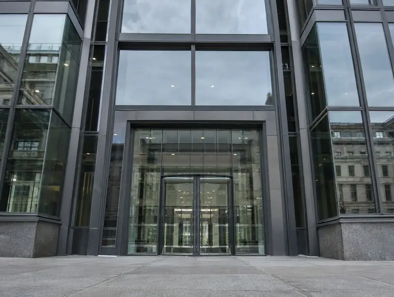 Office building entrance with heavy dark grey aluminium frames and thick glass panels
